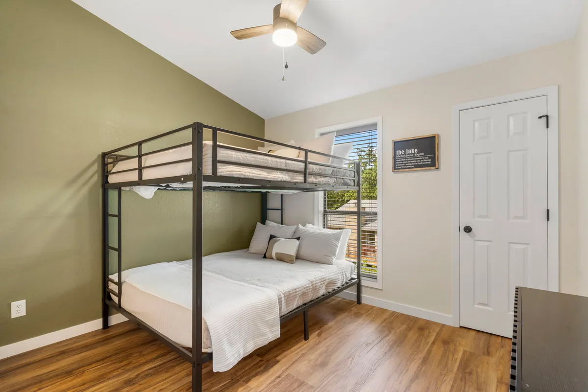 A cozy bedroom with a full-over-full bunk bed, a bright window, and playful wall art. The space looks inviting and comfortable, making it ideal for kids, friends, or families to share a fun and restful night.