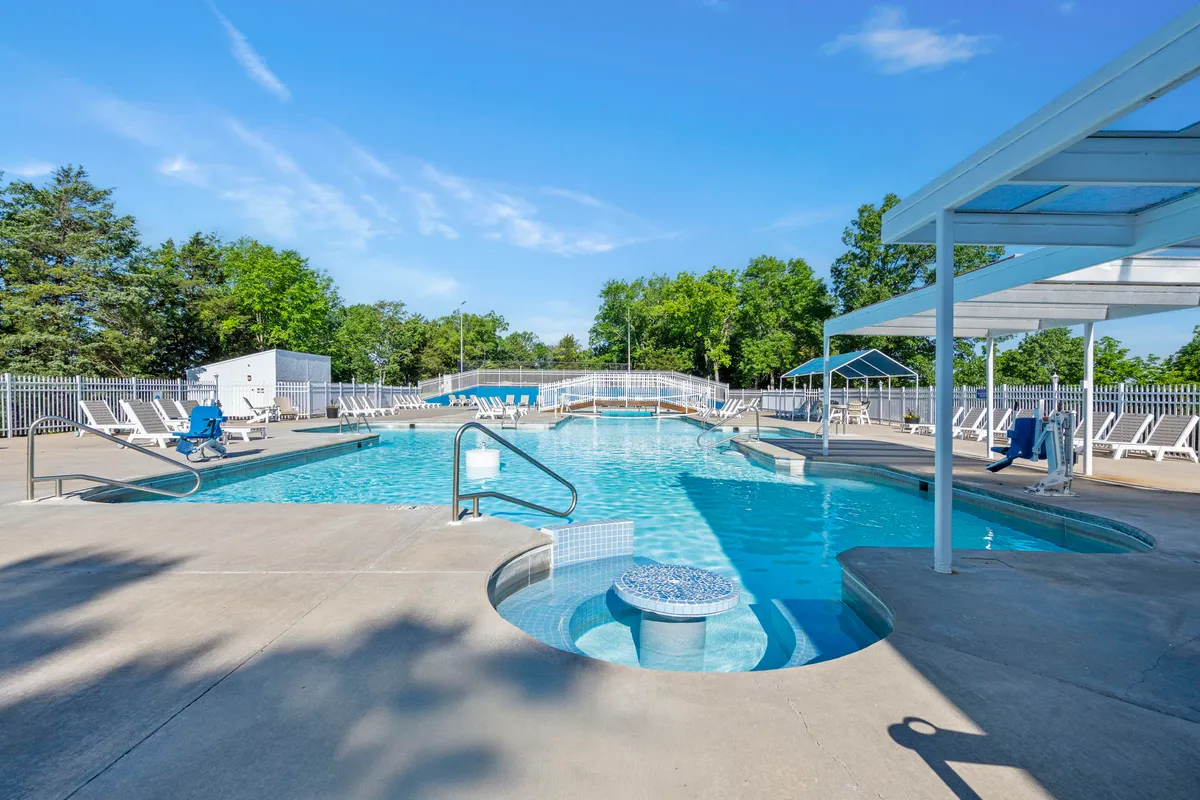 This exterior image showcases a sparkling swimming pool surrounded by lounge chairs and lush greenery. The pool area is inviting, perfect for both relaxation and social gatherings, and hints at fun summer activities under the sun. The overall mood is tranquil and festive, suggesting the enjoyment of seasonal resort amenities.