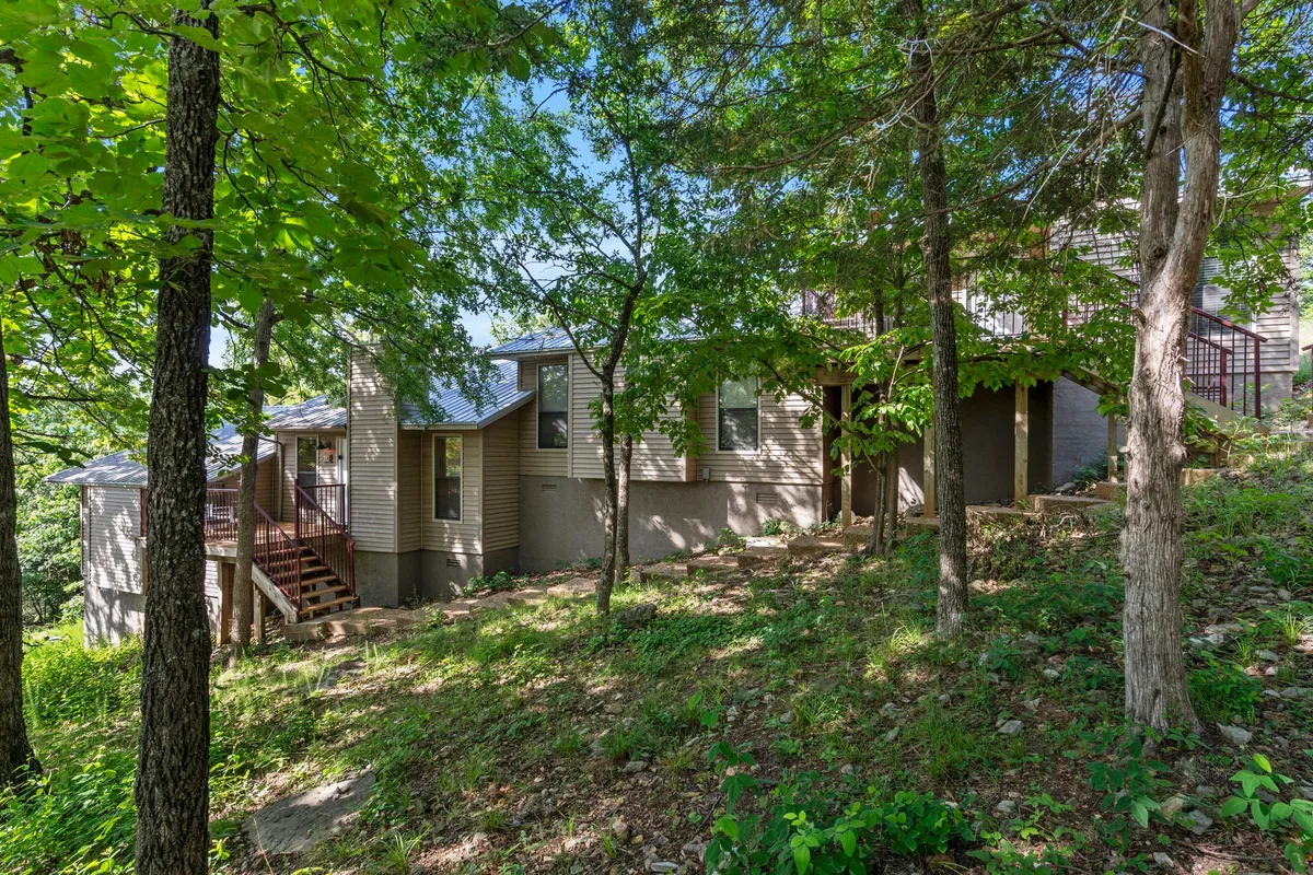 A wooden deck overlooking a sloping yard, surrounded by lush greenery and bordered by the exterior walls of the home. The deck offers a seamless transition from indoor to outdoor spaces, ideal for walks, playtime, and relaxing in nature.