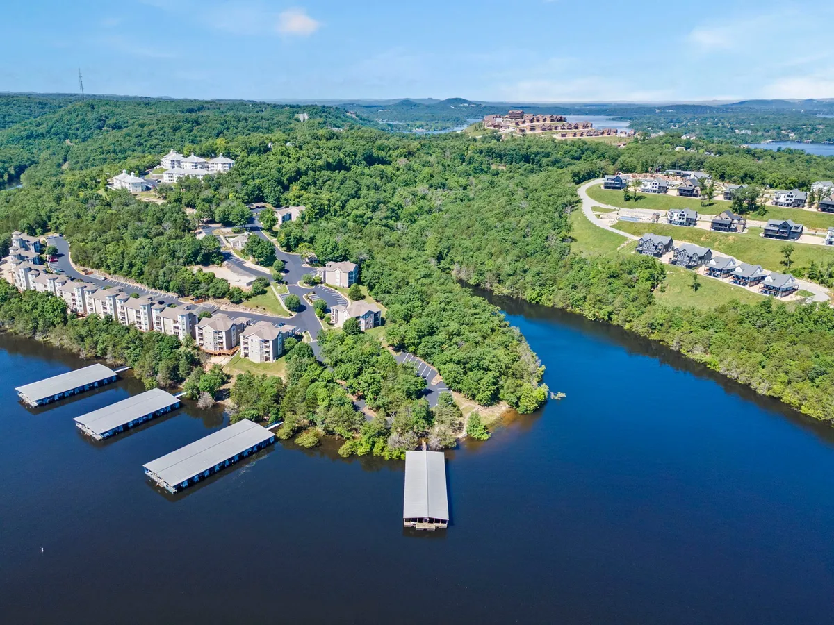 This photo offers a wide view of waterfront docks, residential buildings, and lush greenery. The curved roads and natural setting highlight the community's integration with the lake, while the docks underscore year-round water activities. The scene evokes the feeling of a connected lakeside community.