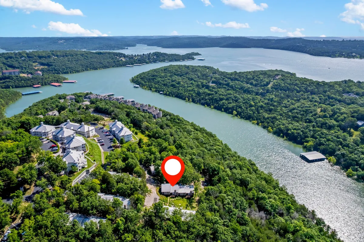 This exterior shot frames the house with the sparkling water just beyond, surrounded by greenery and distant hills. The tranquil water and sunset atmosphere promise restful evenings after a day on the lake, while the proximity of the home to the water is unmistakable.